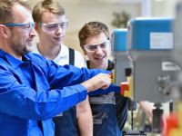 Group of young people in mechanical vocational training with teacher at drilling machine